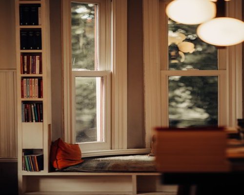 A comfortable reading nook with soft warm lighting next to a large window